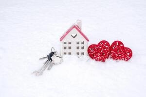 llaves de minúsculo casa y dos corazones en nieve - San Valentín día, amor en hogar. Pareja alojamiento, real bienes, alquilar, hipoteca, reubicación comodidad y calor en amor nido. foto