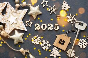 casa llave con llavero cabaña en festivo negro antecedentes con estrellas, luces de guirnaldas nuevo año 2025 de madera letras, saludo tarjeta. compra, construcción, reubicación, hipoteca, seguro foto