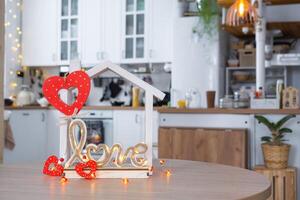 Key to tiny house of cozy home with Valentine decor on table of kitchen. Gift for valentines day, family love nest. design, project, moving to new house, mortgage, rent and purchase real estate photo