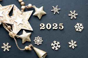 Happy New Year-wooden letters and the numbers 2025 on festive black background with sequins, stars, snow. Greetings, postcard. Calendar, cover photo