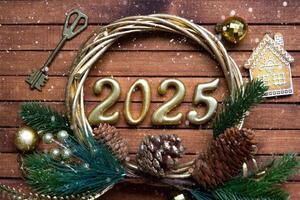 New Year House key with keychain cottage on festive brown wooden background with number 2025 in wreath, lights of garlands. Purchase, construction, relocation, mortgage, insurance photo