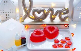 Handmade homemade soap in the shape of hearts for a Valentine's Day gift to your beloved. Perfumes and dyes, soap base on the table photo