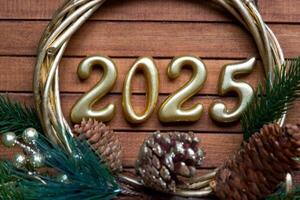 Happy New Year golden numbers 2025 on cozy festive brown wooden background with sequins, snow, lights of garlands. Greetings, postcard. Calendar, cover photo