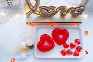 Handmade homemade soap in the shape of hearts for a Valentine's Day gift to your beloved. Perfumes and dyes, soap base on the table photo