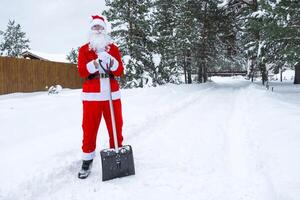 Papa Noel claus limpia nieve con pala en invierno al aire libre después un nevada. limpieza el calles en el aldea, claro el paso para carros, difícil clima condiciones para Navidad y nuevo año foto
