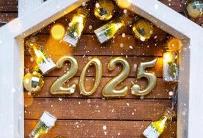 nuevo año 2025 dorado letras debajo techo casa. calendario, saludo tarjeta. compra, construcción, reubicación, hipoteca, seguro foto
