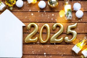 House key with tiny figure of home mock up on festive brown wooden background, lights of garlands. New Year 2025 wooden letters, greeting card. Purchase, construction, relocation, mortgage, insurance photo