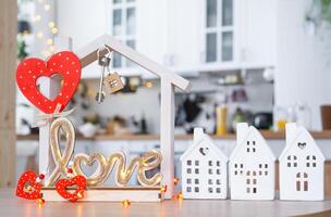 llave a minúsculo casa de acogedor hogar con enamorado decoración en mesa de cocina. regalo para san valentin día, familia amor nido. diseño, proyecto, Moviente a nuevo casa, hipoteca, alquilar y compra real inmuebles foto