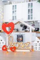 Key to tiny house of cozy home with Valentine decor on table of kitchen. Gift for valentines day, family love nest. design, project, moving to new house, mortgage, rent and purchase real estate photo