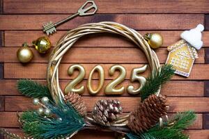 New Year House key with keychain cottage on festive brown wooden background with number 2025 in wreath, lights of garlands. Purchase, construction, relocation, mortgage, insurance photo