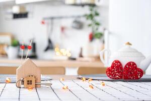 Key to tiny house of cozy home with Valentine decor on table of kitchen. Gift for valentines day, family love nest. design, project, moving to new house, mortgage, rent and purchase real estate photo