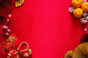 Chinese new year concept with red envelope packets or ang bao word mean auspice, red bag, ingots word mean wealth and oranges on red cloth background. photo