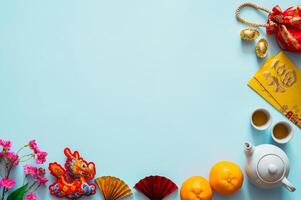 Chinese new year background with tea set, envelope packets or ang bao word mean blessing, red bag, ingots word mean wealth, hanging pendant dragon and oranges on blue background photo