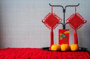 A red envelope or ang pao words mean dragon and good luck with hanging pendants and oranges on the tray for Chinese new year concept. photo