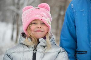 A girl in a snowy park. Photo of a child in a winter forest. Winter, winter holidays, vacations, vacations.