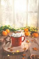 Cute cozy winter composition. red mug, marshmallows, oranges and Christmas lights. photo