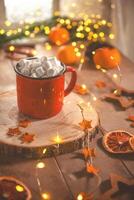 Cute cozy winter composition. red mug, marshmallows, oranges and Christmas lights. photo