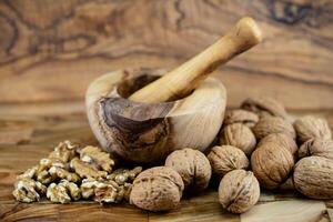 Fresh and cracked walnuts on olive wood photo