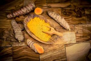 Turmeric Curcuma longa the yellow spice on olive wood photo