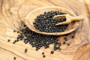 a stack of peppercorns on olive wood photo