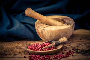 a stack of peppercorns on olive wood photo