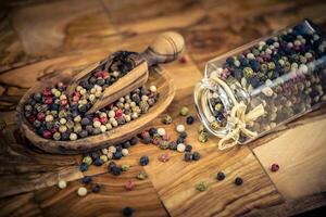 a stack of peppercorns on olive wood photo