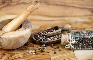 a stack of peppercorns on olive wood photo