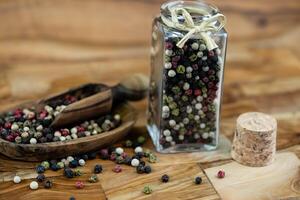 a stack of peppercorns on olive wood photo