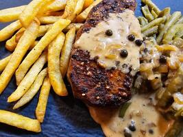 francés filete a la pimienta con verde pimienta verde frijoles y pommes patatas fritas foto