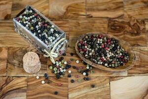 a stack of peppercorns on olive wood photo