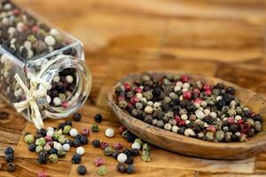 a stack of peppercorns on olive wood photo