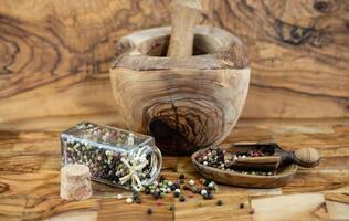 a stack of peppercorns on olive wood photo