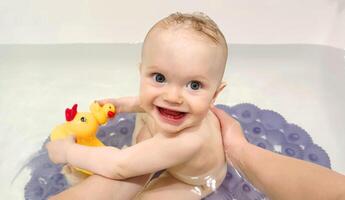 linda 8 mes antiguo niña se baña en un bañera con patitos foto