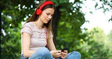 Woman listening to music sitting on bench in a park photo