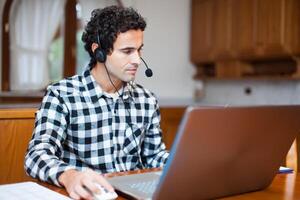 Guy using headset and laptop computer, chatting on Internet photo