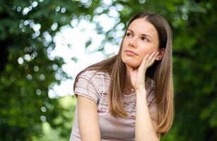 portrait of a pretty thoughtful lady sitting on a banch in a park photo