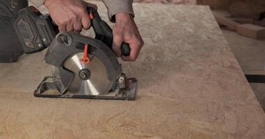 A worker uses a circular saw to cut plywood. Construction of a new wooden house using frame technology. The concept of building wooden houses. video