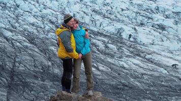 contento un' uomo e un' donna In piedi contro il fondale di un' ghiacciaio. skaftafell nazionale parco. Islanda. 4k video