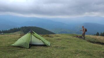 uma homem com uma mochila viaja dentro a montanhas. acampamento vida, fuga a partir de cidade. conceito do aventura, viagem. lento movimento cenas 4k video