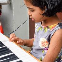 Asian cute girl playing the synthesizer or piano. Cute little kid learning how to play piano. Child's hands on the keyboard indoor. photo