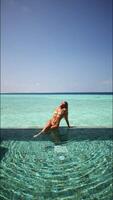 Girl in bikini sitting by the pool in the Maldives. vertical footage video