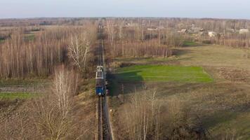 Aerial view of A locomotive and two carriages move along a narrow gauge railway in the countryside. video