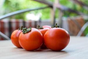Red tomato on plain wooden table, essential vegetables for all essential foods, view of unpeeled vegetables with plain background photo