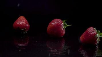 Strawberry slow motion closeup falling in water with Splash droplets on black background macro shot cooking video