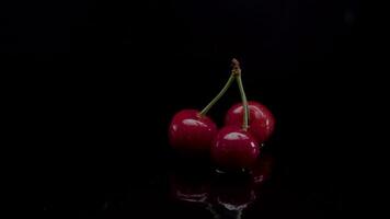 Cherry slow motion closeup falling in water with Splash droplets on black background macro shot cooking video