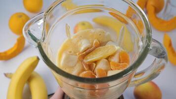 frukt smoothie blandad i blandare. orange, banan, äpple i en blandare, topp se. friska och vegetarian mat begrepp video