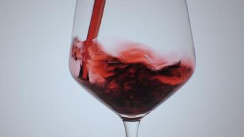 rojo vino formas hermosa ola. vino torrencial en vino vaso en blanco antecedentes. de cerca disparo. video