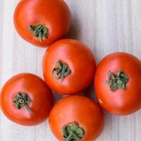 Red tomato on plain wooden table, essential vegetables for all essential foods, view of unpeeled vegetables with plain background photo