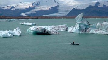 un' barca galleggiante attraverso un' fusione ghiacciaio laguna a jokulsarlon, Islanda. 4k video