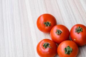 Red tomato on plain wooden table, essential vegetables for all essential foods, view of unpeeled vegetables with plain background photo